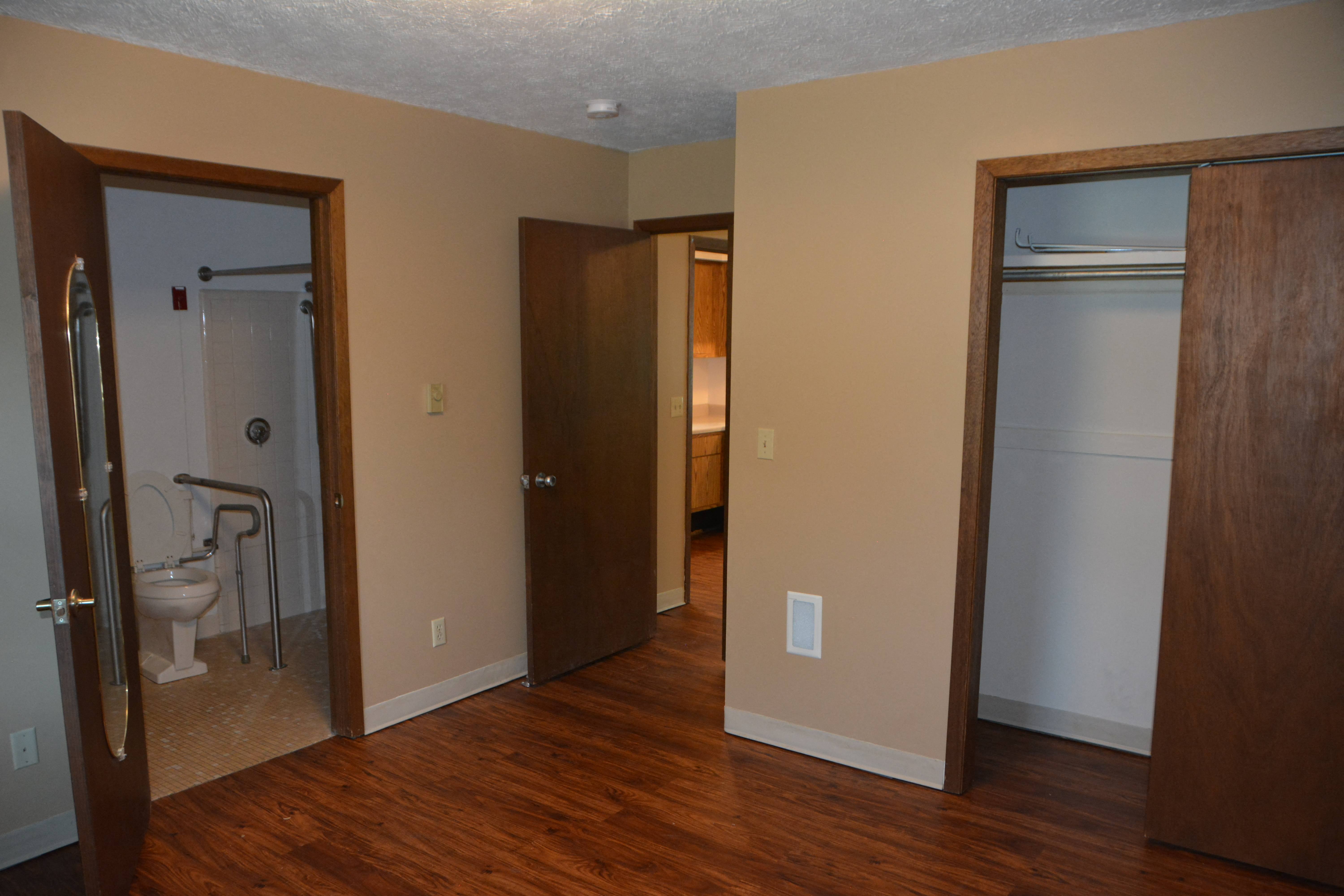 a living room with a door to a bathroom and a closet